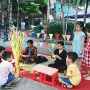 Hình ảnh nghệ nhân xếp lá dừa tại một sự kiện cùng các bé giao lưu